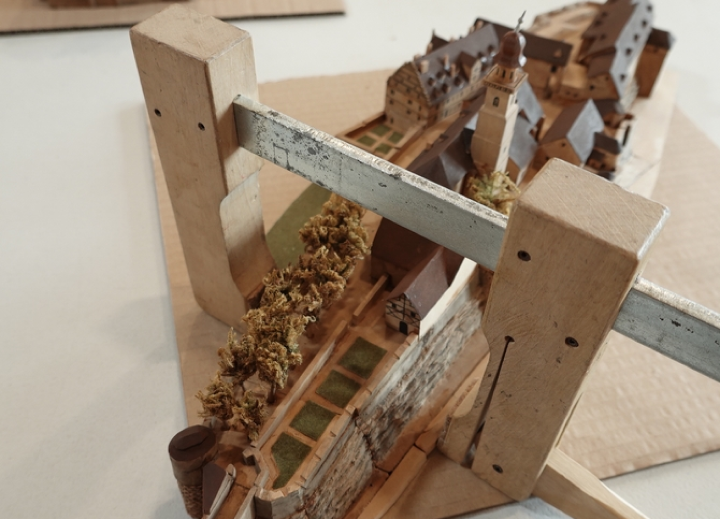 image_1_restauration Maquette historique en bois représentant un site patrimonial, maintenue par une structure de conservation.
