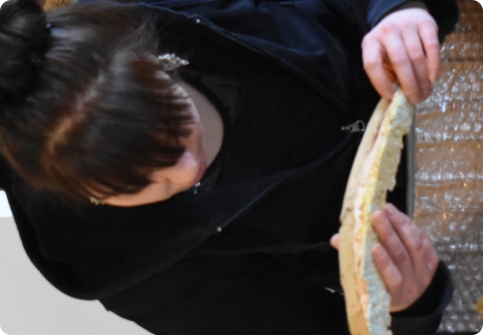 Jeune femme observant un fragment de moulage ou de fossile en atelier de conservation.